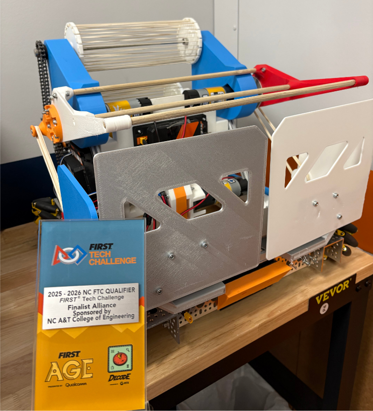 A colorful FIRST Tech Challenge robot with a roller mechanism stands next to its Finalist Alliance award plaque. TITLE