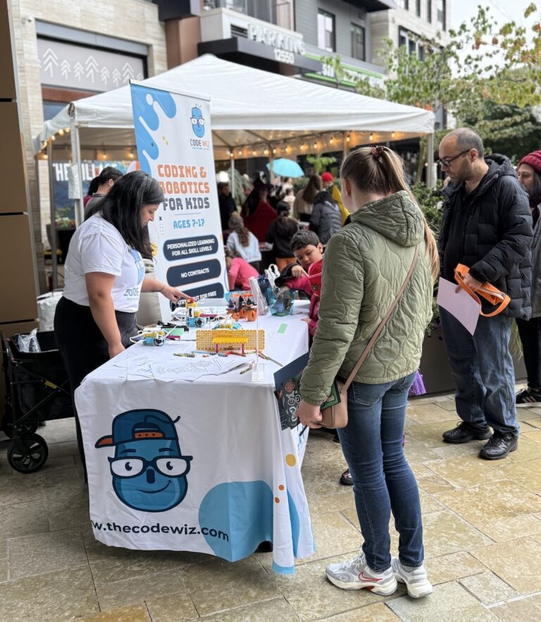 A Code Wiz booth at an outdoor event, featuring coding and robotics activities for children.