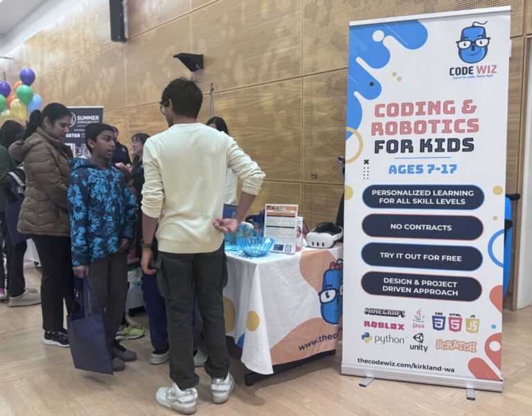 Attendees, including children, interact at a Code Wiz booth promoting coding and robotics programs. TITLE
