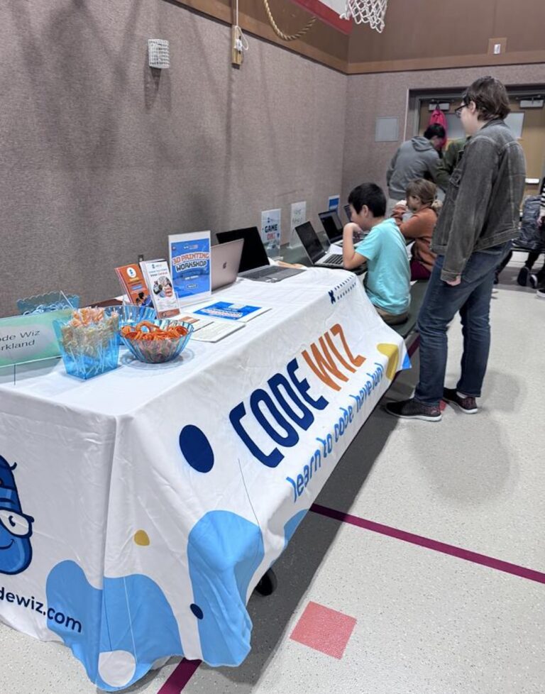 Students engage with laptops at a Code Wiz booth promoting coding and 3D printing workshops.