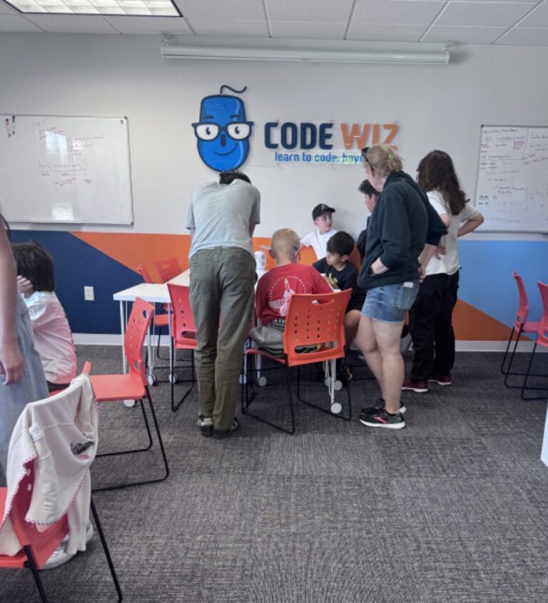 Young students learn coding with instructors in a vibrant Code Wiz classroom.