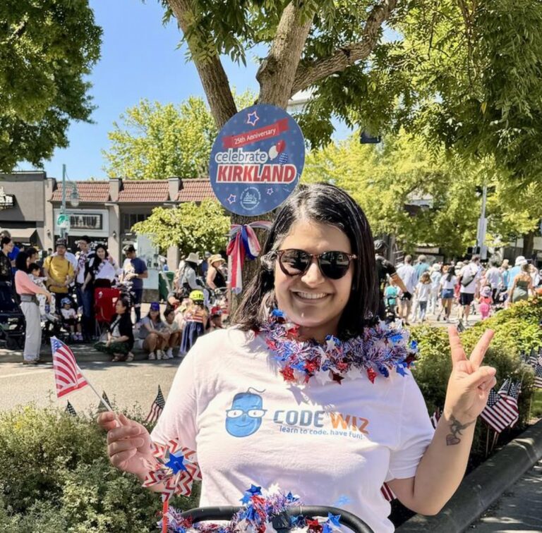Happy woman in a Code Wiz shirt and patriotic garland celebrates Kirkland's 2
