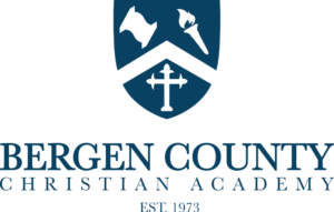 Bergen County Christian Academy logo featuring a shield with a scroll, torch, and cross
