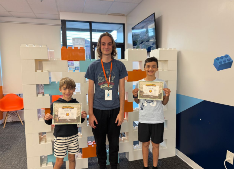 Two boys proudly display their Code Combat certificates alongside an instructor.