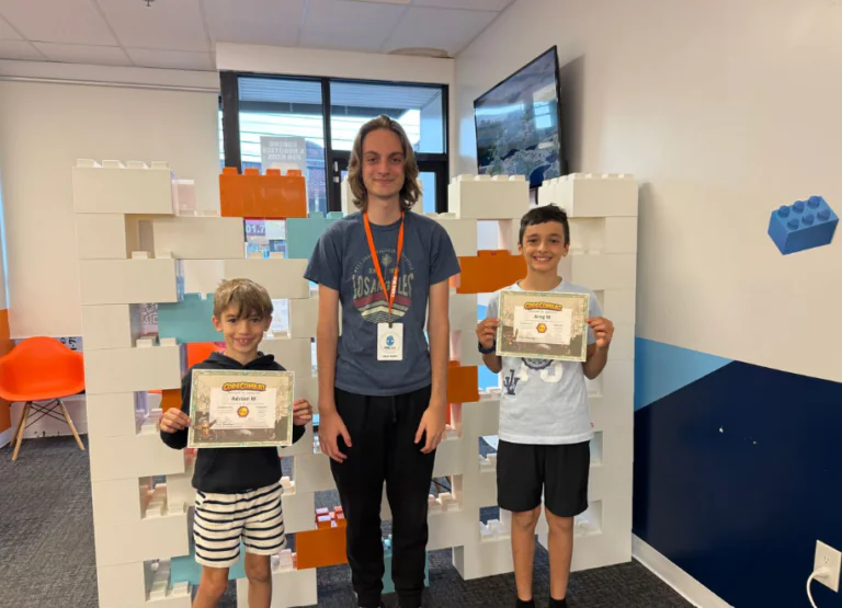 Two boys proudly display their Code Combat certificates alongside an instructor.