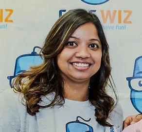 A cheerful woman with long, highlighted brown hair smiles at the camera.