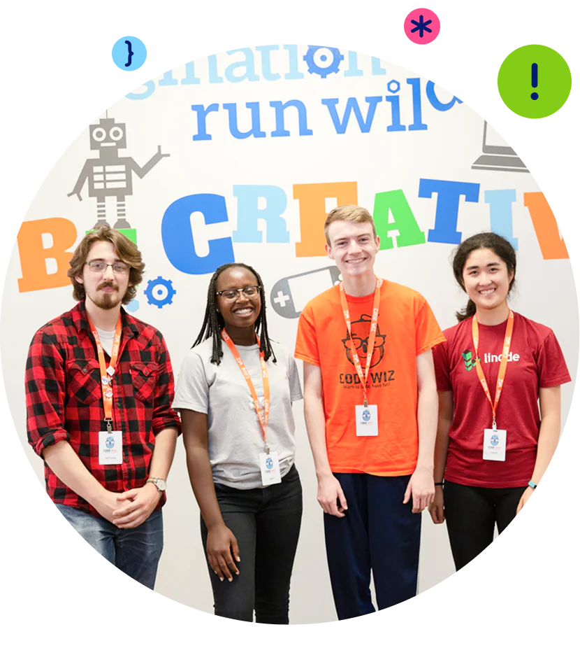 A diverse group of four smiling students wearing lanyards stands before a colorful "Be Creative