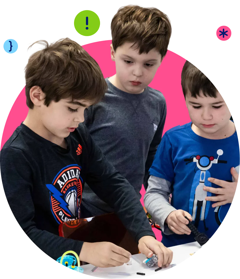 Three young boys are focused on building with small parts at a table.