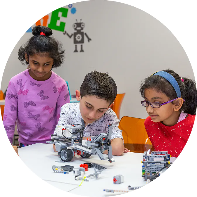 Three children intently build a robot with building blocks, engaged in a STEAM learning activity. TITLE